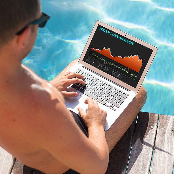 Investor looking at stock quotes on laptop by the pool